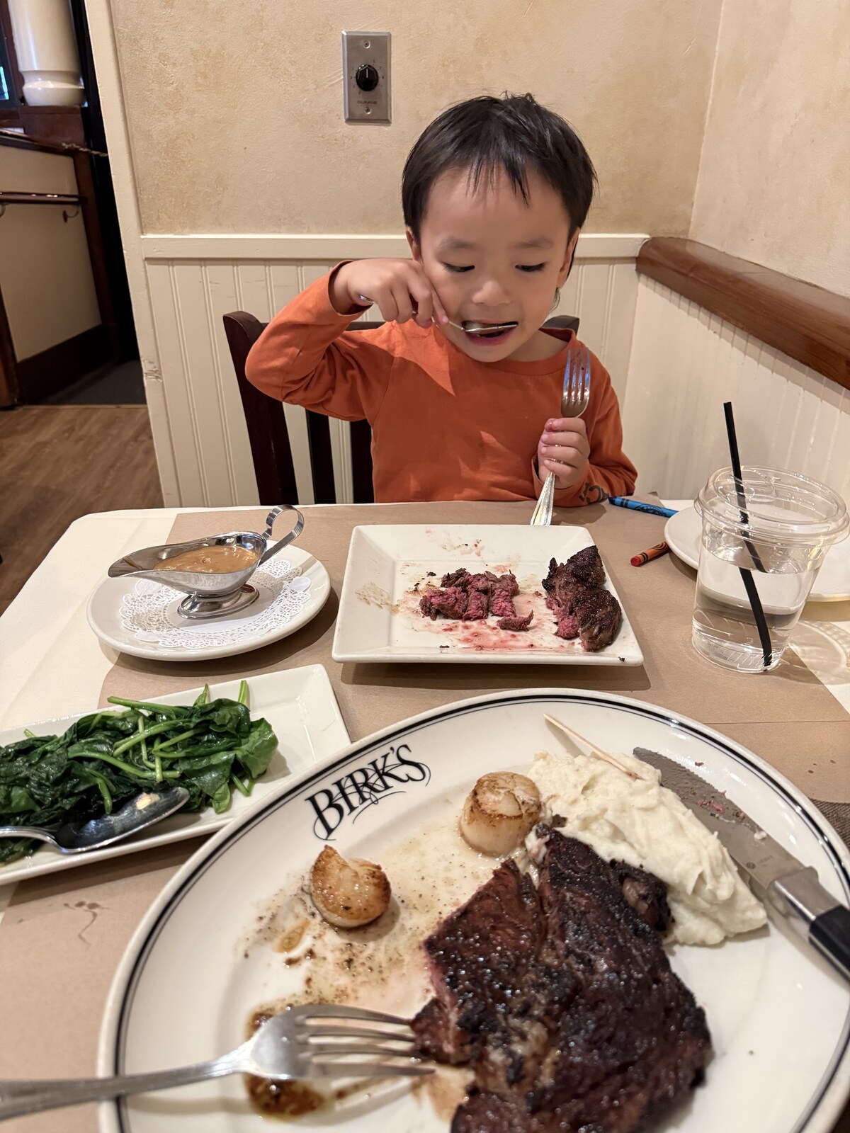Jichang eating steak at Birk's Restaurant with mashed potatoes and spinach on the table