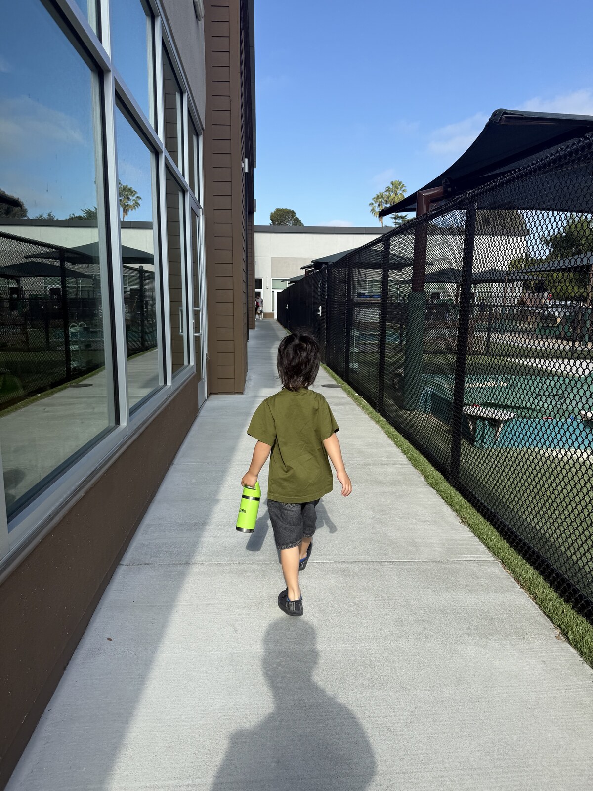 Jichang marching toward the school entrance with a green Yeti water bottle