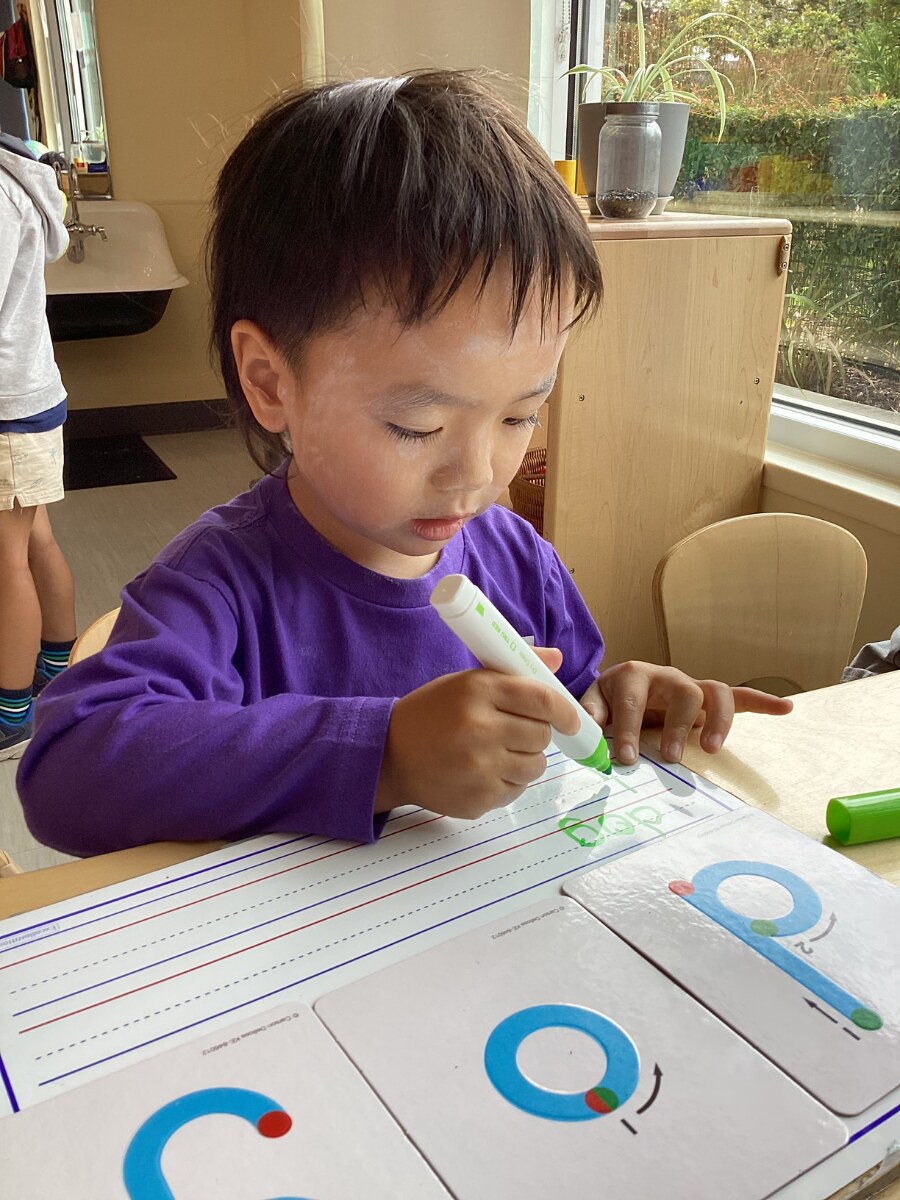 Jichang practicing a three-letter word with letter cards and a whiteboard