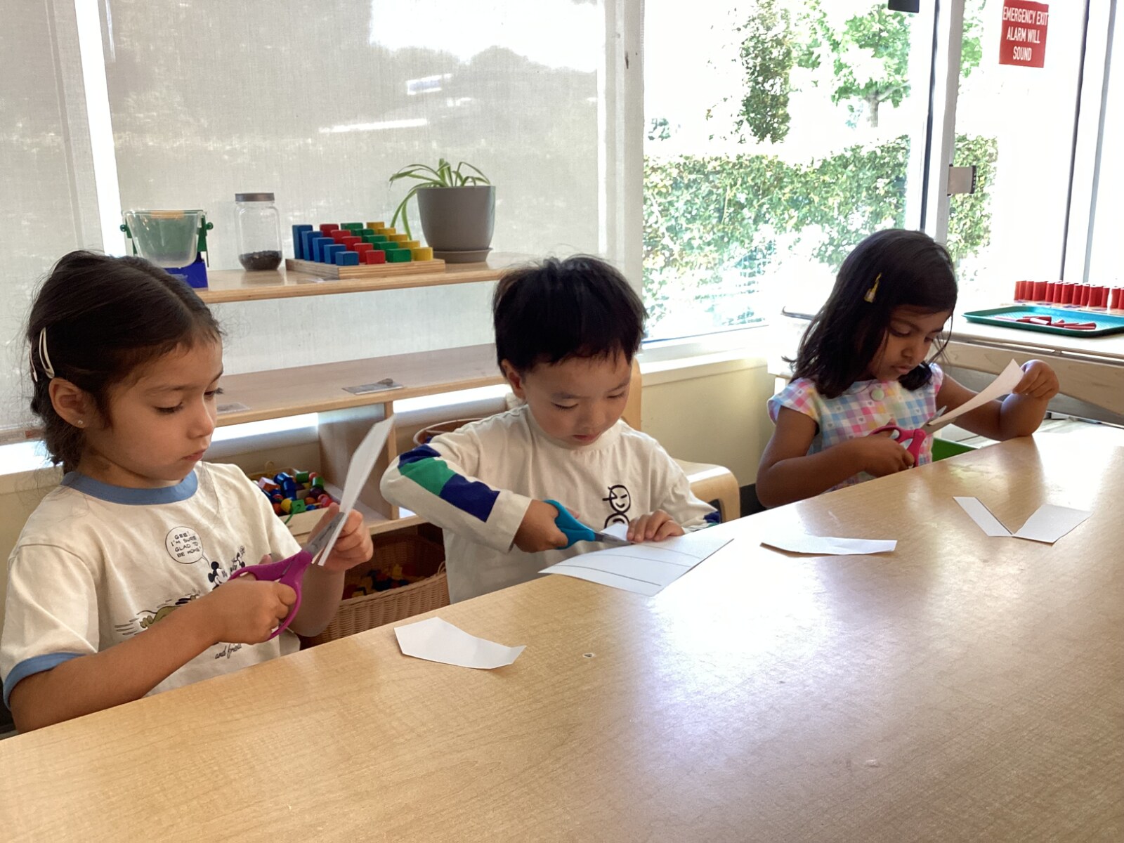 Jichang and classmates practicing cutting paper with scissors at school