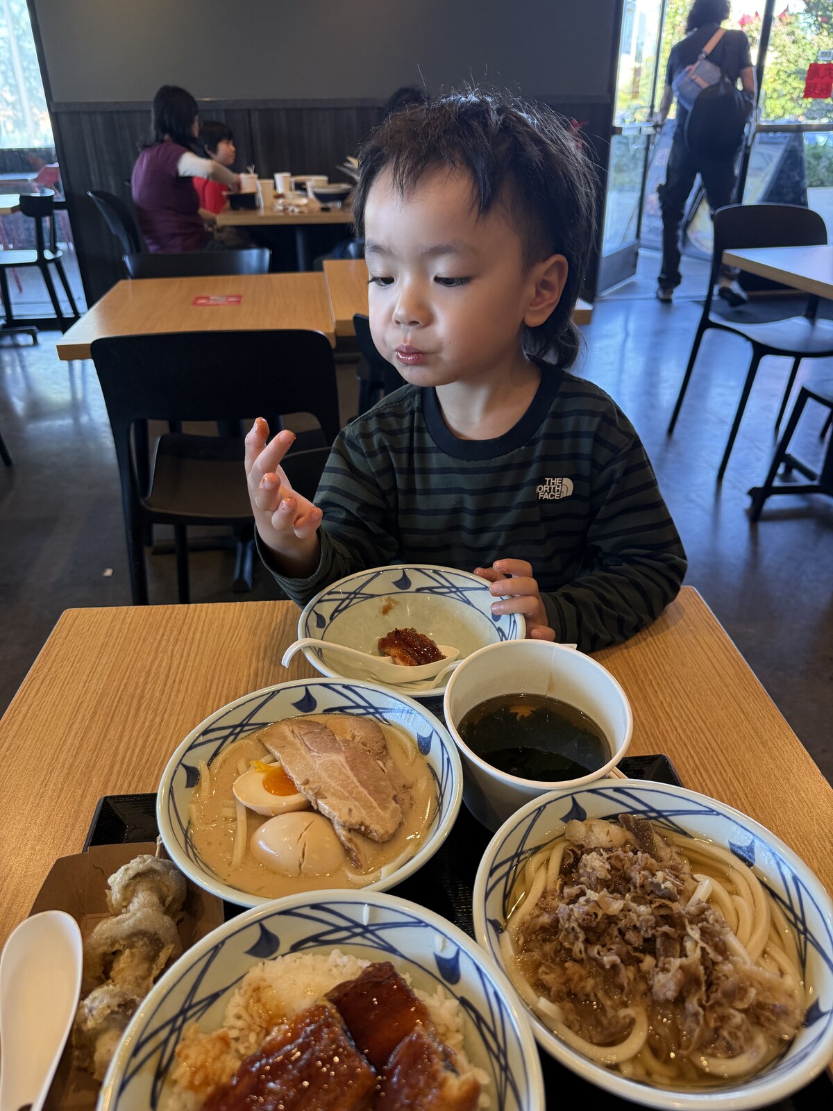 Jichang dipping his finger into eel sauce during an udon dinner