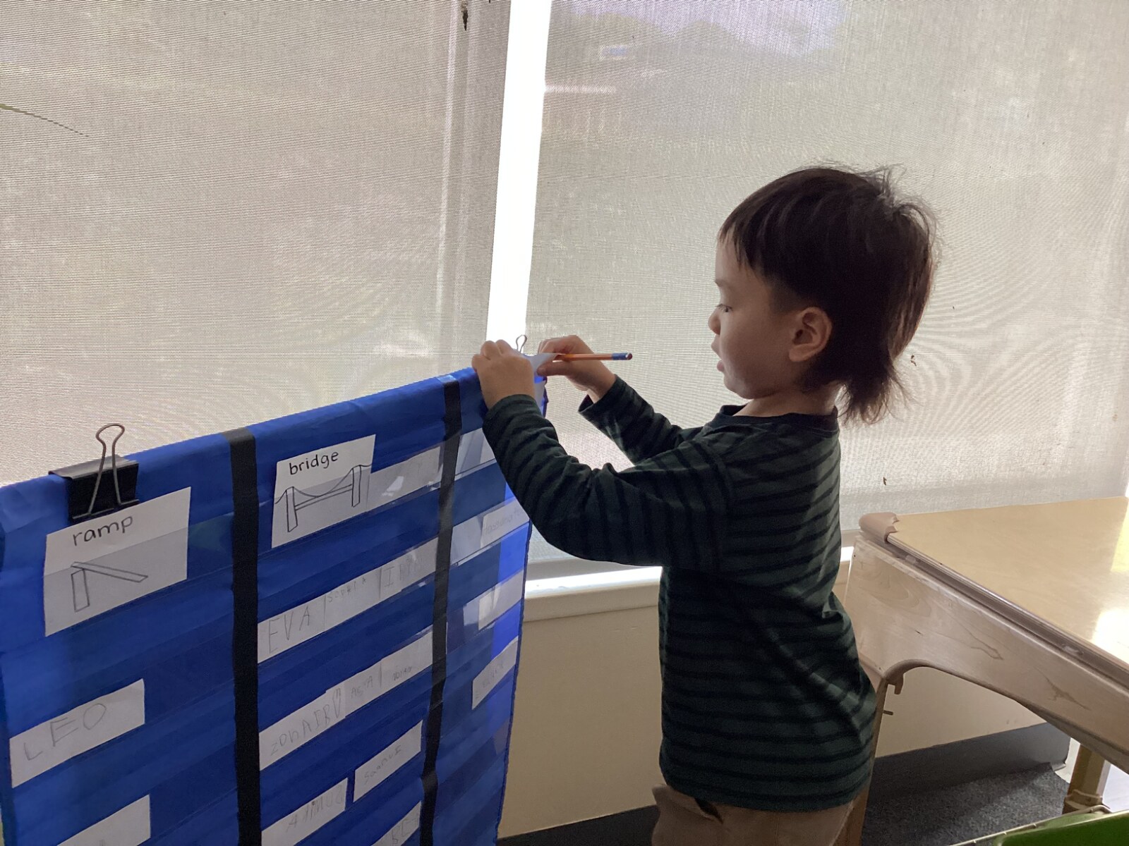 Jichang signing in at Bright Horizons and choosing tower on a classroom chart
