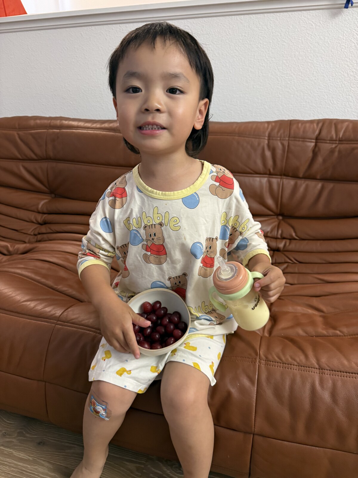 Jichang sitting on the couch after dinner with a bowl of grapes