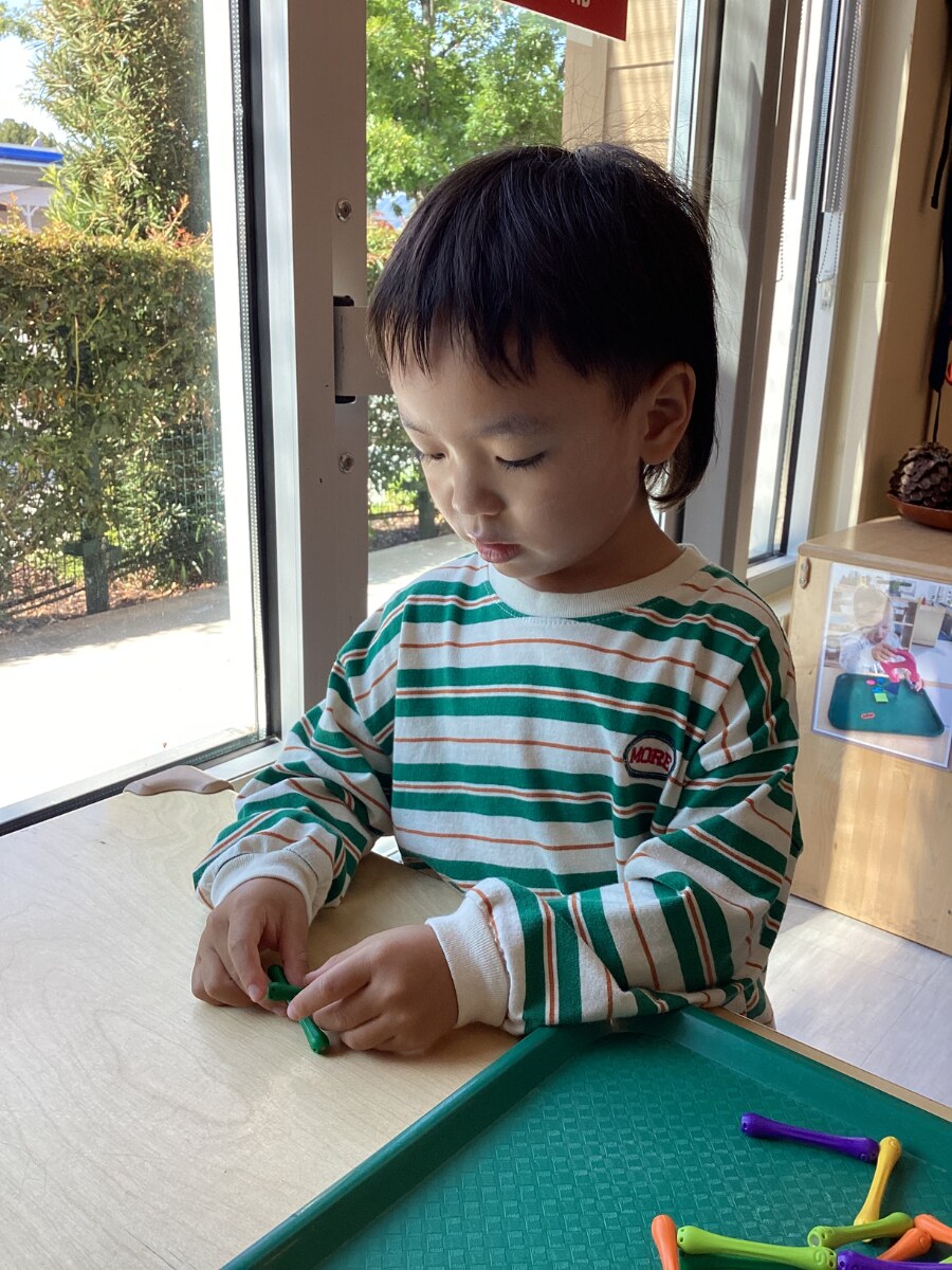 Jichang practicing uppercase letters with colorful magnet bars at school