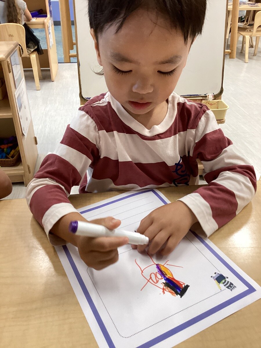 Jichang drawing a self-portrait at school with colored pencils
