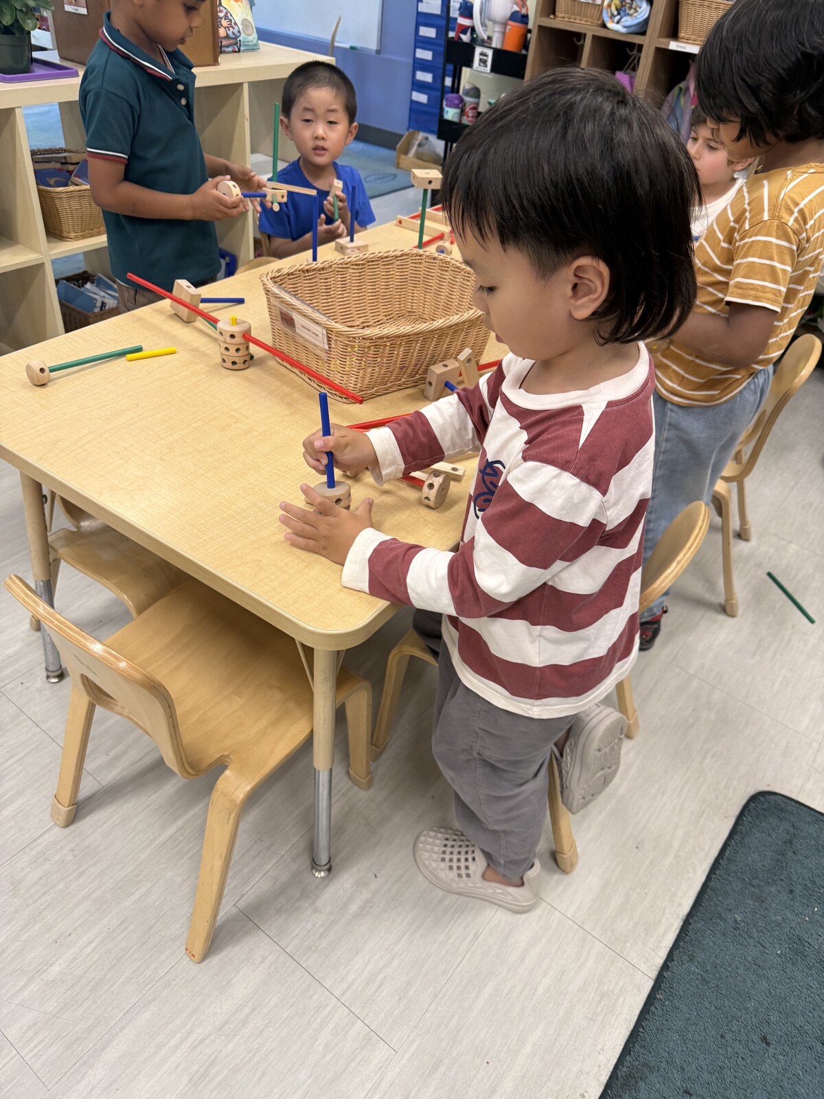 Jichang playing at a Bright Horizons table while Daddy waits at pickup