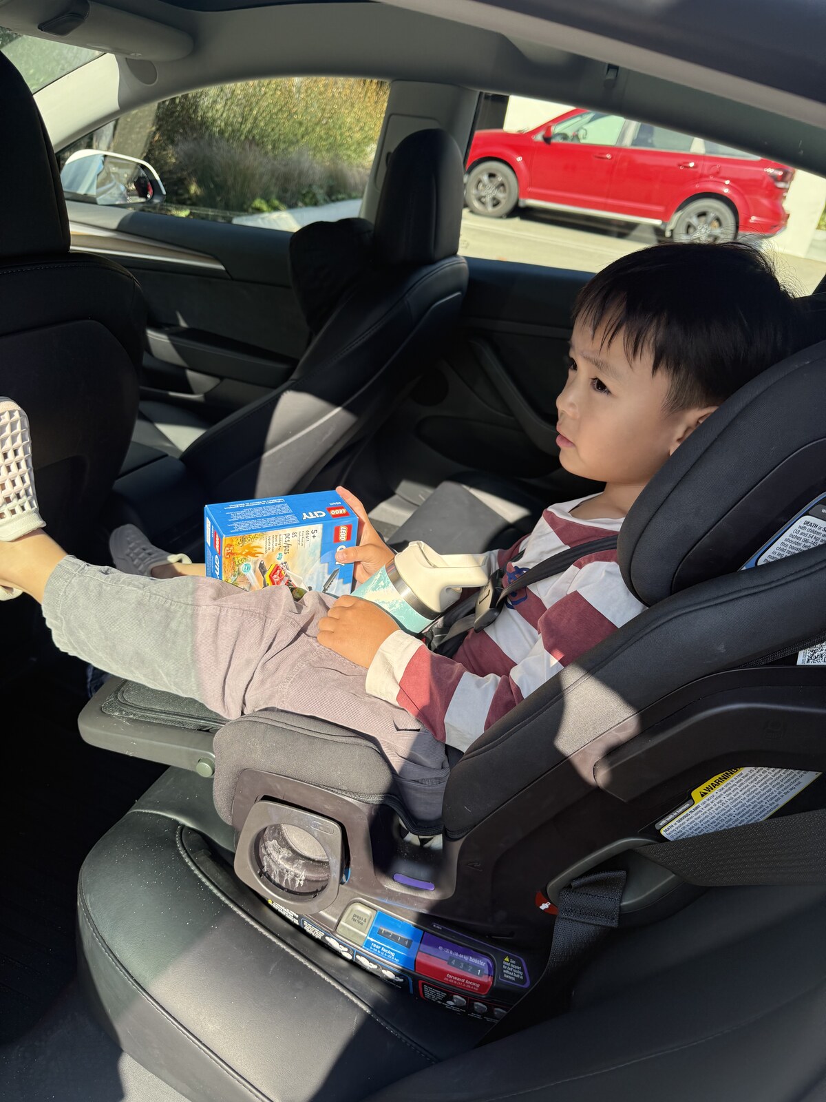 Jichang sitting in the car seat with a new Lego goodie bag