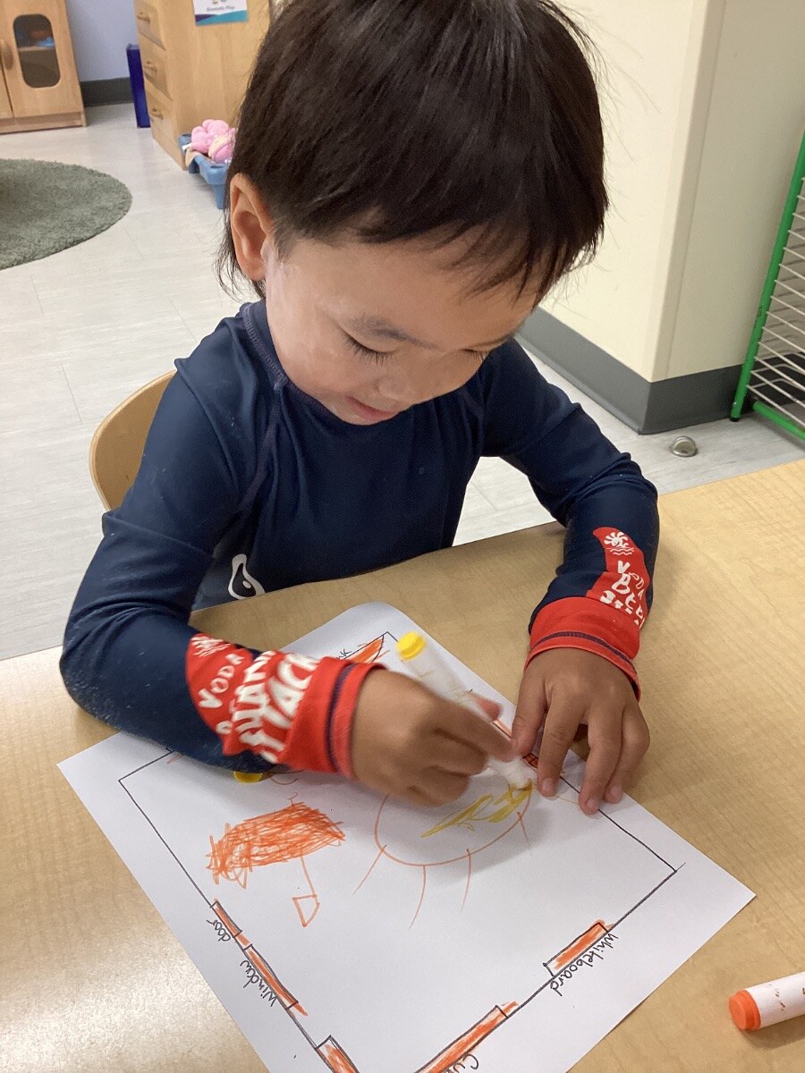 Jichang drawing a colorful picture at a classroom table