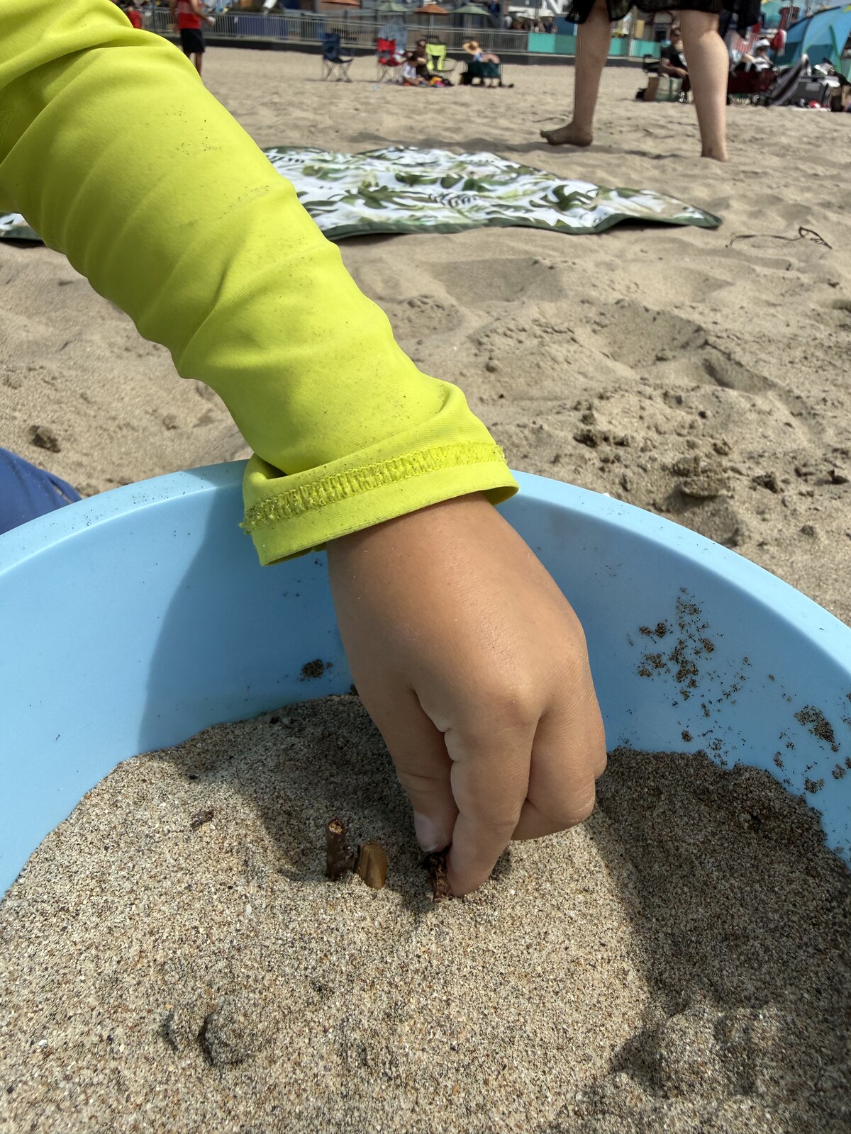 Jichang adding candle shapes to a sand birthday cake at the beach