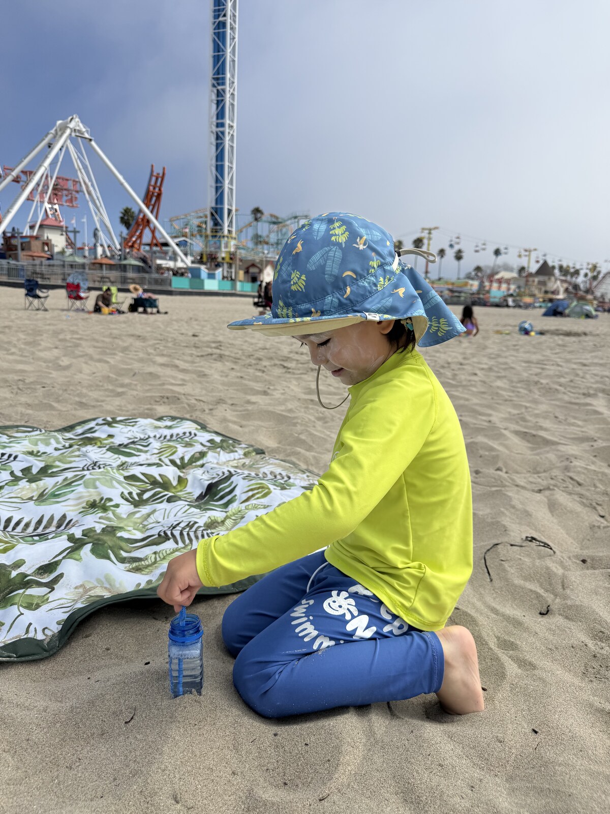 Jichang stirring sand inside a bubble bottle at the beach
