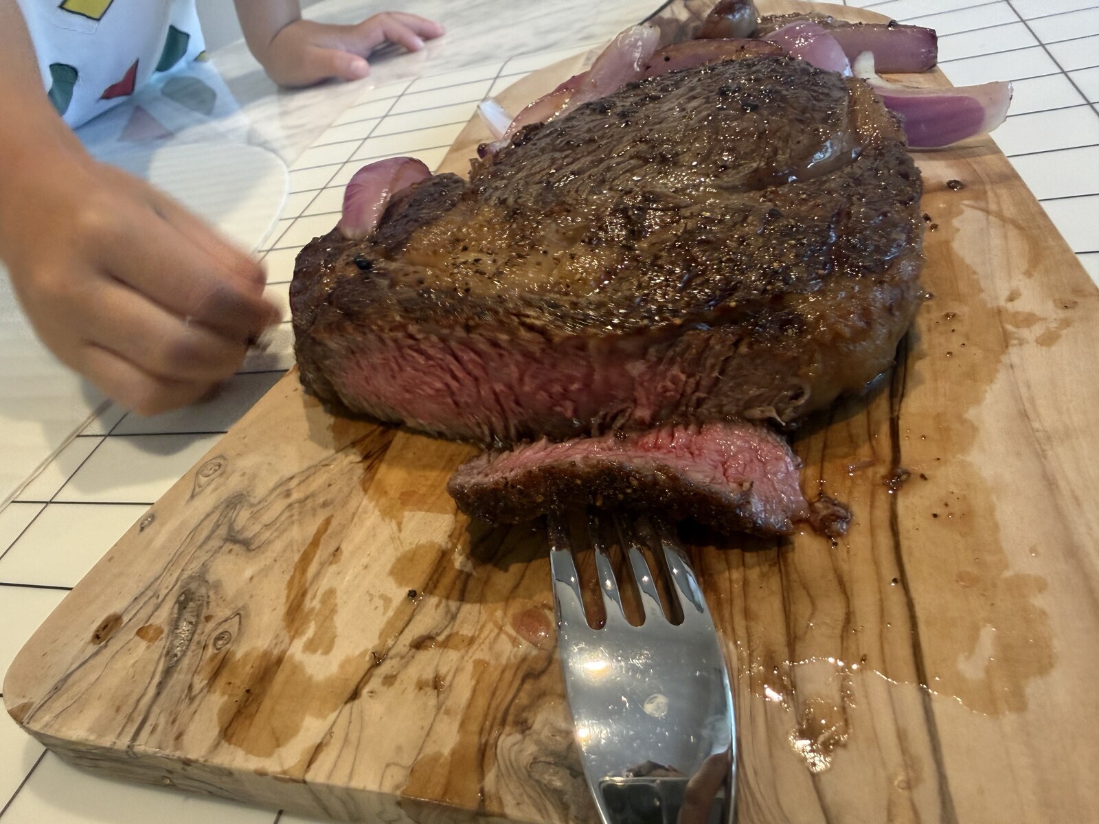 Sliced medium well steak with onions on a cutting board